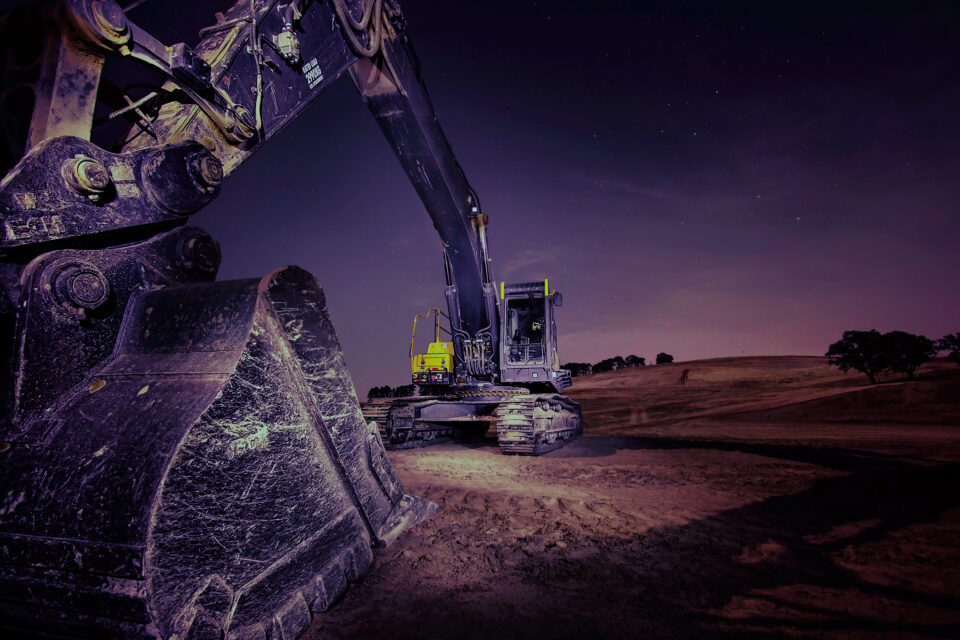 Excavator on a graded development site at dusk