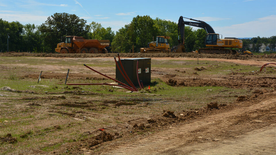 Transformer and conduit stub-ups on a new development site with earthmoving equipment